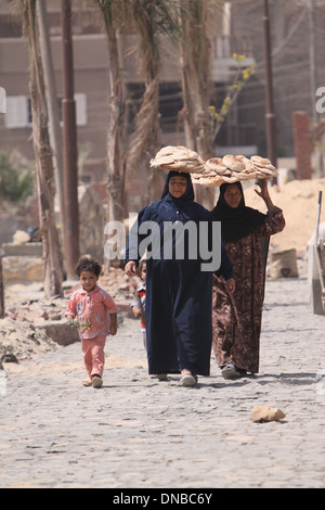 Deux femmes portant sur leur tête de pain- Egypte El Fayoum - de la difficulté de la vie . Banque D'Images