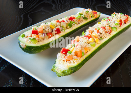 Deux courgettes farcies au quinoa et les légumes sur une plaque blanche Banque D'Images