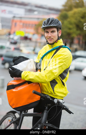 La mise en paquet de cyclistes masculins Courier Bag On Street Banque D'Images