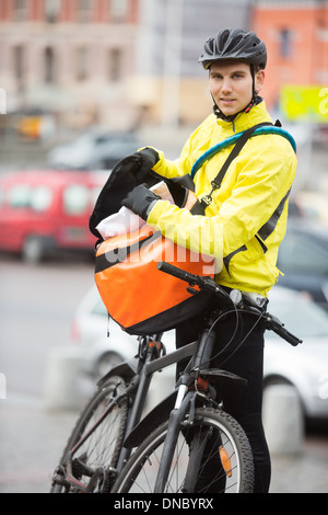 La mise en paquet de cyclistes masculins Courier Bag On Street Banque D'Images