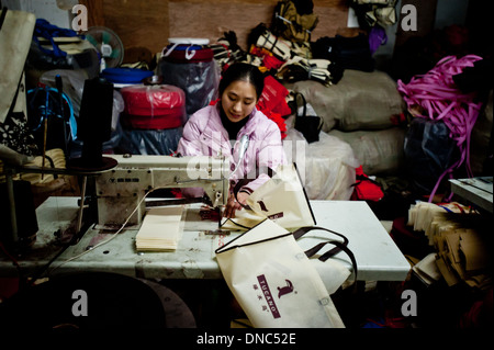 Chongqing, Chine - 31 décembre 2010 : une femme chinoise coud un sac de pièces sur une machine à coudre dans une usine textile. Banque D'Images