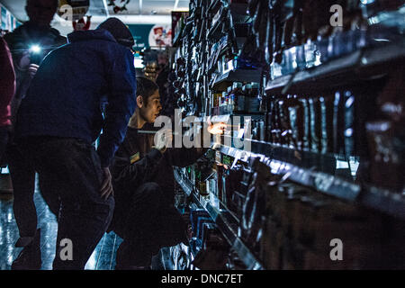 Pays de Galles Aberystwyth UK. Dec 22, 2013. Les gens shopping par la lumière des flambeaux et les téléphones mobiles dans la direction de Aberystwyth Poundland le dernier dimanche avant Noël. Une coupure de courant à environ 12,45 caviardé les principales rues commerçantes de la ville , forçant la plupart des magasins à proximité. Poundland seulement resté ouvert avec le personnel en route voir ce qu'ils achetaient. Scottish Power, le fournisseur local, devrait avoir l'électricité rétablie par 15,00 ou 16,00 sources disent Crédit photo : Keith morris/Alamy Live News Banque D'Images