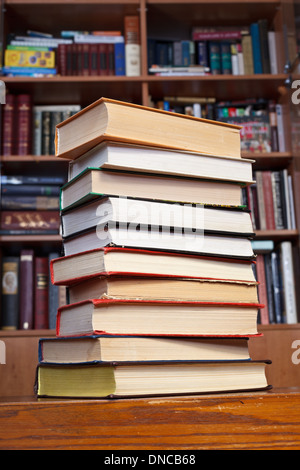 Pile de livres sur la table en bois près de bibliothèques Banque D'Images