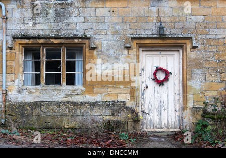 Cotswold cottage historique avec anneau et peeling bienvenue porte peinte, Cotswolds, Gloucestershire, England, UK Banque D'Images