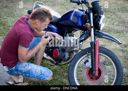 18 adolescents polonais soufflant sur bougie alors que la réparation de sa moto. Zawady Centre de la Pologne Banque D'Images