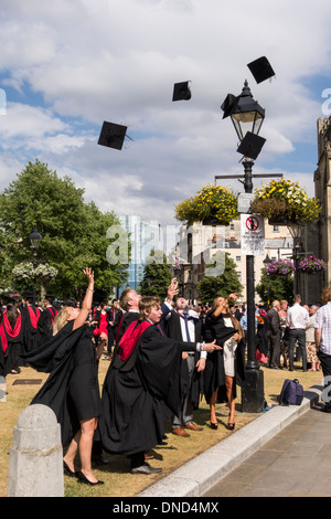 Graduates throwing mortarboards leur après la cérémonie. Cérémonie de remise des diplômes à l'UWE College Green, Bristol, Royaume-Uni Banque D'Images