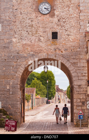 Un couple marche hors de la vieille porte dans la partie ancienne de Noyers sur Serein en Bourgogne. Banque D'Images