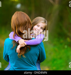 Maman holding daughter kid fille dans ses bras vue arrière smiling in outdoor Banque D'Images