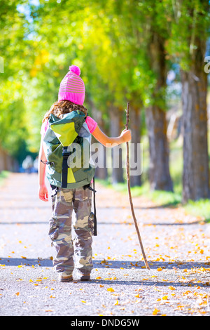 Randonnées kid girl avec bâton de marche et sac à dos vue arrière à l'automne la voie et pantalon camouflage Banque D'Images