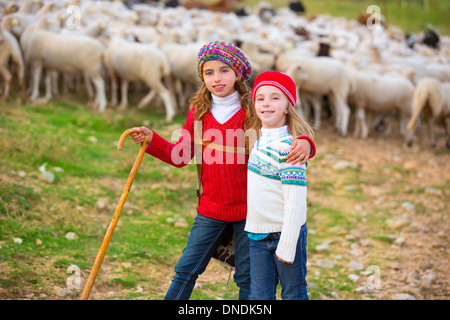 Kid girl bergère sœurs heureux avec troupeau de moutons et bâton en bois en Espagne Banque D'Images