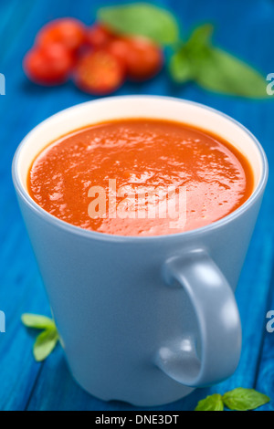Soupe de tomates fraîches maison servi dans la tasse bleu sur bleu en bois (Selective Focus, Focus un tiers dans la soupe) Banque D'Images
