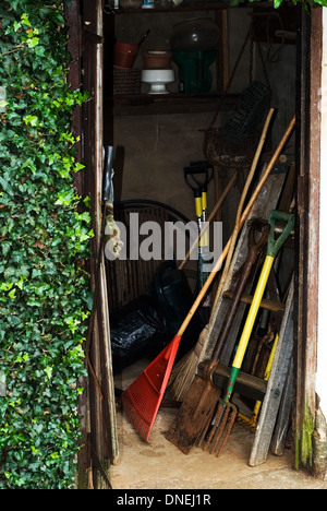 Ouvrez la porte de l'ancien abri de jardin avec le râteau et autres outils de jardinage. Banque D'Images