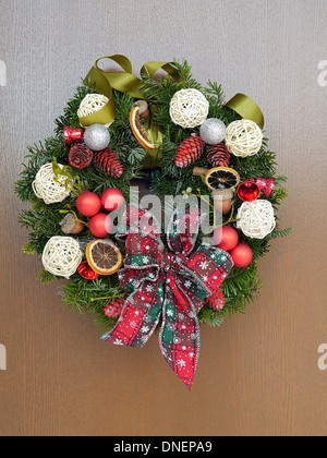 Couronne de Noël avec des décorations et ribbon bow attaché à la porte en bois Banque D'Images