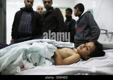 Deir el Balah, dans la bande de Gaza. 24 décembre 2013. Un garçon palestinien blessé est perçu sur un lit à l'hôpital d'Al-Aqsa à Deir el Balah. Le mardi Israël a effectué une série de raids aériens et d'artillerie sur la bande de Gaza, tuant une fille palestinienne et en blessant au moins cinq autres, en réaction aux premières embusqués de Gaza qui a tué un travailleur israélien sur la frontière de séparation. (Xinhua/Wissam Nassar/Alamy Live News) Banque D'Images