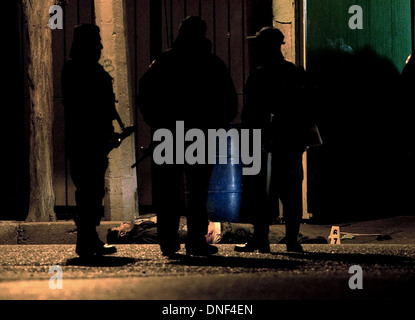 Un enquêteur de police examine le corps d'un homme tué par cartel qu'il a rendu visite à sa famille le 14 janvier 2009 à Juarez, au Mexique. Le tournage, liée à la drogue en cours à une guerre qui a déjà fait plus de 40 personnes depuis le début de l'année. Plus de 1600 personnes ont été tuées à Juarez en 2008, faisant de la ville la plus violente Juarez au Mexique. Banque D'Images