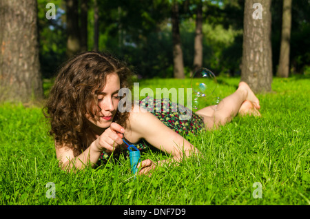 Young Pretty woman blowing soap bubbles in park Banque D'Images