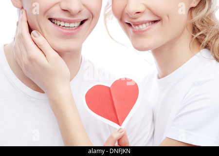 Close-up of young girl holding amoureux coeur rouge et toucher son petit ami Banque D'Images