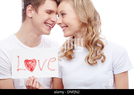 Portrait of young couple smiling girl holding tout en papier avec mot amour Banque D'Images