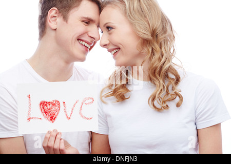 Portrait of young couple smiling girl holding tout en papier avec mot amour Banque D'Images