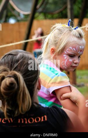 Jeune avec son visage peint est assis sur les genoux de sa mère lors d'un festival à Sarasota FL Banque D'Images