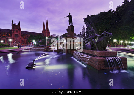 Australie sydney Hyde Park central fontaine Archibald au coucher du soleil avec la cathédrale St Mary de l'eau brouillée monument illuminé Banque D'Images