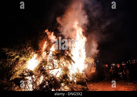 Thessalonique, Grèce. Le 24 décembre, 2013. Les gens regarder le début de l'incendie majeur au centre de Florina. La veille de Noël de la ville de Florina en Grèce du Nord et les villages environnants une tradition particulière se fait appelé ãƒæ'Ã'àƒ¢â''àƒ ?š š ?l''firesÃƒAE'Ã'Â'''Àƒæ Sàƒæ ?š Â''. Au cours de cet événement les habitants des grands incendies dans chaque partie de la ville. Cette tradition est dit que éloigne les mauvais esprits et symbolise les bergers qui visitent le nouveau-né le Christ. L'éclat de l'incendie devrait réchauffer l'enfant. Autour du feu, les habitants et les touristes de la danse, de boire du vin et manger de la soupe de haricots.Photo : Gianni Banque D'Images