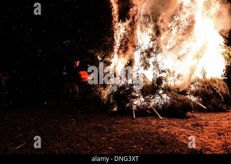 Thessalonique, Grèce. Le 24 décembre, 2013. Un homme se jette sur le feu du gaz au cours de la veille de Noël. La veille de Noël de la ville de Florina en Grèce du Nord et les villages environnants une tradition particulière se fait appelé ãƒæ'Ã'àƒ¢â''àƒ ?š š ?l''firesÃƒAE'Ã'Â'''Àƒæ Sàƒæ ?š Â''. Au cours de cet événement les habitants des grands incendies dans chaque partie de la ville. Cette tradition est dit que éloigne les mauvais esprits et symbolise les bergers qui visitent le nouveau-né le Christ. L'éclat de l'incendie devrait réchauffer l'enfant. Autour du feu, les habitants et les touristes de la danse, de boire du vin et manger de la soupe de haricots.Photo : Giannis Papanikos/ Banque D'Images