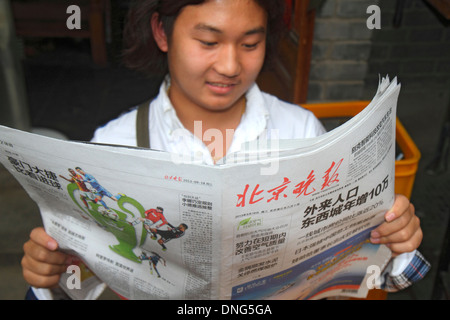 Beijing Chine,Chinois,Dongcheng District,Nanluoguxiang,hutong,Chinois caractères hànzì pinyin,asiatique homme hommes,lecture,journal,tabloïd,China130918 Banque D'Images