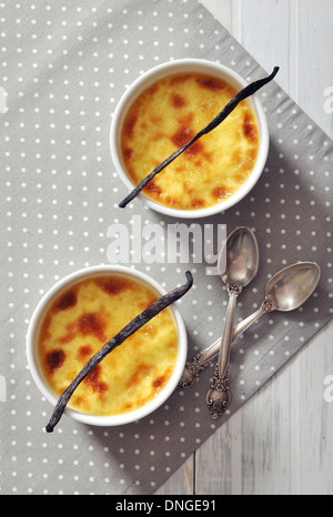 La crème brûlée à la cuisson en céramique moule avec la gousse de vanille sur table en bois Banque D'Images