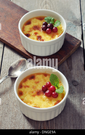 La crème brûlée en céramique moule à pâtisserie avec la menthe et les petits fruits sur table en bois Banque D'Images