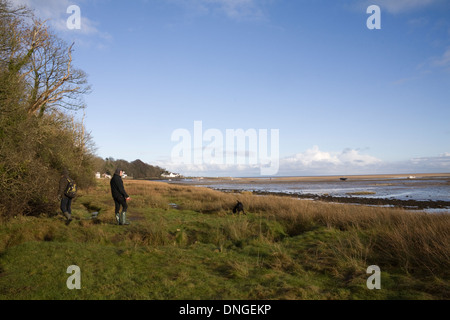 Quai rouge Bay Ile d'Anglesey au nord du Pays de Galles UK Deux hommes marcher un chien le long de la côte en direction de la baie Banque D'Images