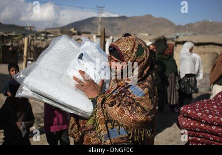 Kaboul, Afghanistan. 28 Dec, 2013. Une femme afghane effectue des fournitures de secours d'hiver offert par le gouvernement allemand pour les personnes déplacées à Kaboul, Afghanistan, le 28 décembre 2013. © Ahmad Massoud/Xinhua/Alamy Live News Banque D'Images