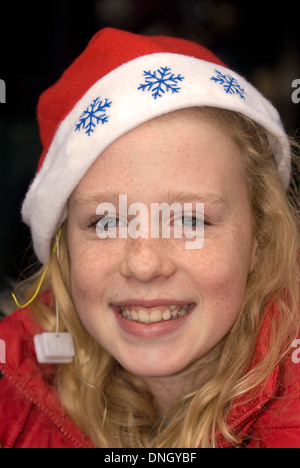 12 ans, fille, wearing christmas hat à un marché de Noël annuel, Petersfield, Hampshire, Royaume-Uni. Banque D'Images