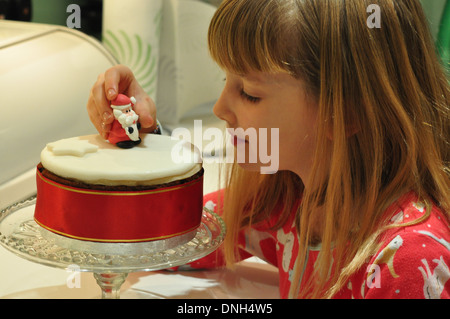 Petite fille décore le gâteau de Noël Banque D'Images