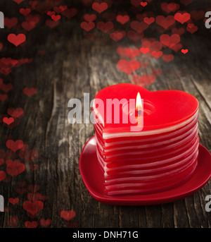 La combustion de bougies en forme de coeur rouge sur fond de bois. Banque D'Images