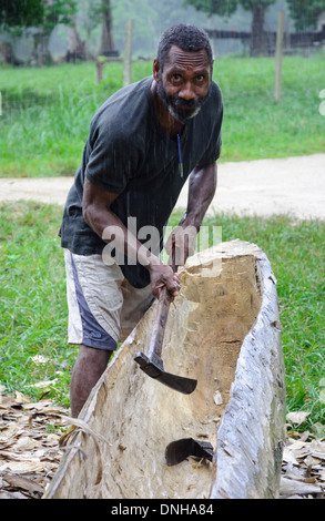 L'homme faisant une pirogue avec une hache, à la manière traditionnelle. Banque D'Images