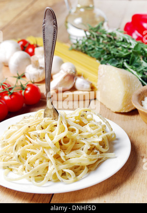 Les pâtes avec la sauce et les herbes dans la plaque blanche sur la table en bois Banque D'Images