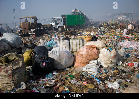 Sacs remplis de matériaux recyclables s'asseoir près d'un camion de déchets toxiques à la décharge de Stung Meanchey à Phnom Penh, Cambodge. Banque D'Images