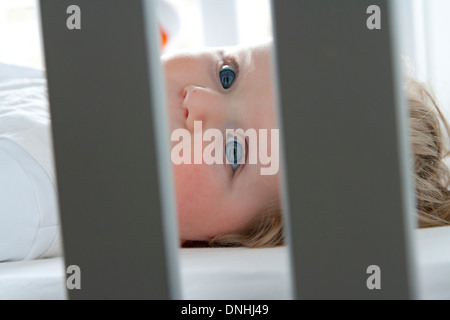 Bébé fille blonde aux yeux bleus au lit Banque D'Images