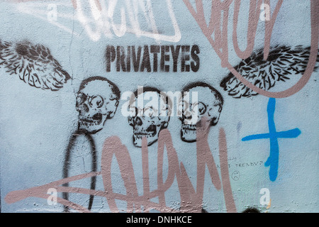 Street art stencil 'Private Eyes' - trois crânes et ailes Heneage street - Brick Lane, East London, UK Banque D'Images