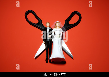 Miniature en plastique chiffres mariage avec des ciseaux sur un fond rouge. Banque D'Images