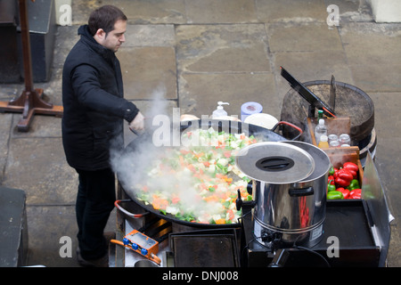 La cuisine de l'homme sur un sauté au wok un géant dans un marché en dehors de Londres Banque D'Images