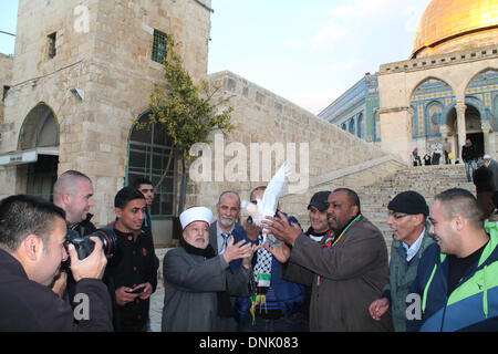 Ahmad Khalaf regarde un chef religieux ainsi que d'autres de presse une colombe à l'extérieur de la mosquée al-Aqsa le jour après qu'il a été libéré d'une prison israélienne, dans la vieille ville de Jérusalem le 31 décembre 2013. Israël a libéré 26 prisonniers palestiniens, le mardi, les jours avant le Secrétaire d'Etat John Kerry était dû retourner au Moyen-Orient pour presser les deux parties de convenir d'un cadre de l'accord de paix. Banque D'Images
