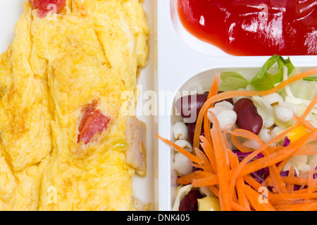 Des omelettes avec salade fraîche dans la boîte en plastique blanc. Banque D'Images