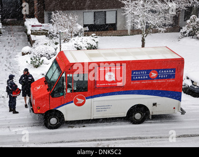 La livraison du courrier sur un jour neigeux Vancouver. Un transporteur lettre parle brièvement à un autre travailleur de Postes Canada dans un camion de livraison. Banque D'Images