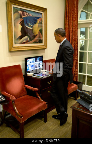 Le président américain Barack Obama regarde la couverture médiatique de la disparition de Nelson Mandela dans le bureau ovale extérieur le 5 décembre 2013 à Washington, DC. Banque D'Images