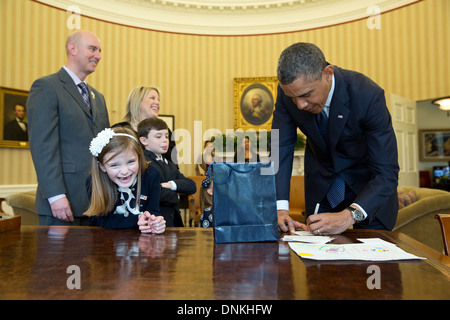 Le président américain Barack Obama signe un heureux souvenirs pour Nina Centofanti, 8, la Marche des dix sous 2013 ambassadeur national dans le bureau ovale de la Maison Blanche le 26 mars 2013 à Washington, DC. Banque D'Images