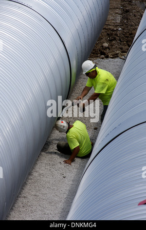 Les hommes de la construction travaillent sur l'installation de rétention des eaux de ruissellement souterrain de tuyaux Banque D'Images