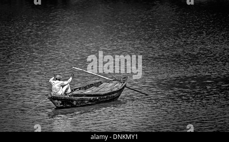 Un pêcheur de l'ouest du Bengale de pêche de Rivière Damodar bateau de son pays en noir et blanc et copy space Banque D'Images