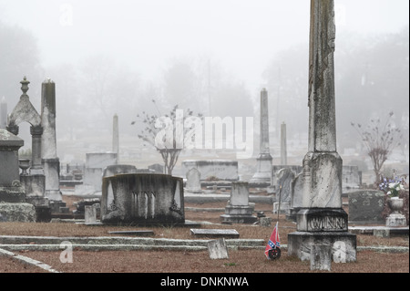 Une médaille et un drapeau confédéré d'anciens combattants accompagnent un marqueur de tombe dans un cimetière couvert de brouillard à Lawrenceville, en Géorgie. (ÉTATS-UNIS) Banque D'Images